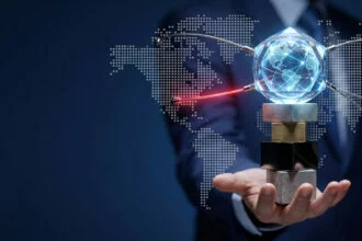 pmk-28-2026-transfer-pricing-compliance-indonesia A businessman's hand balancing a crystal globe and taut network wires on a stack of concrete and metal blocks, symbolizing the high stakes and strict scrutiny of transfer pricing structures under PMK 28/2026.